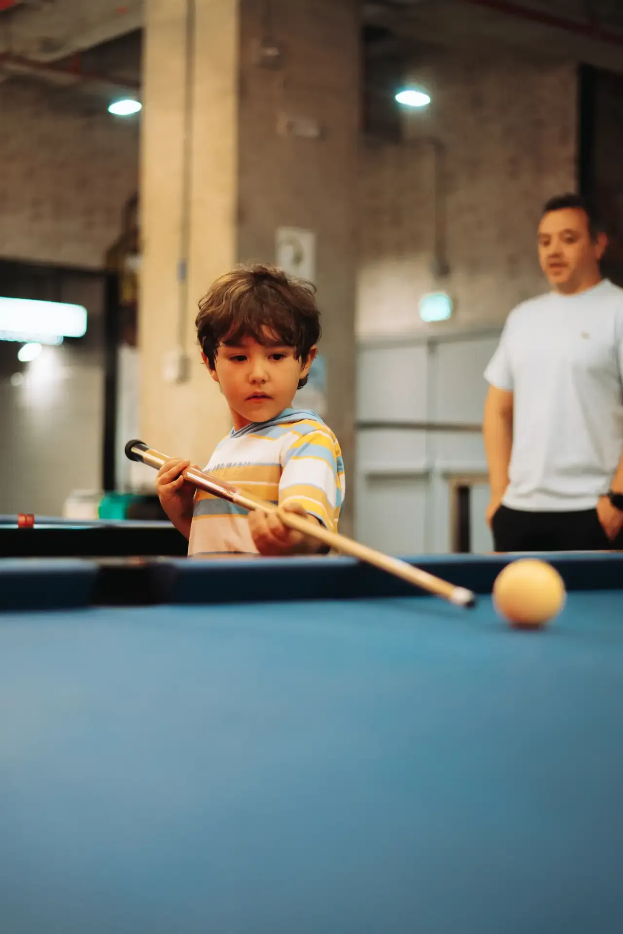 Niño observa una bola sobre la mesa de billar.