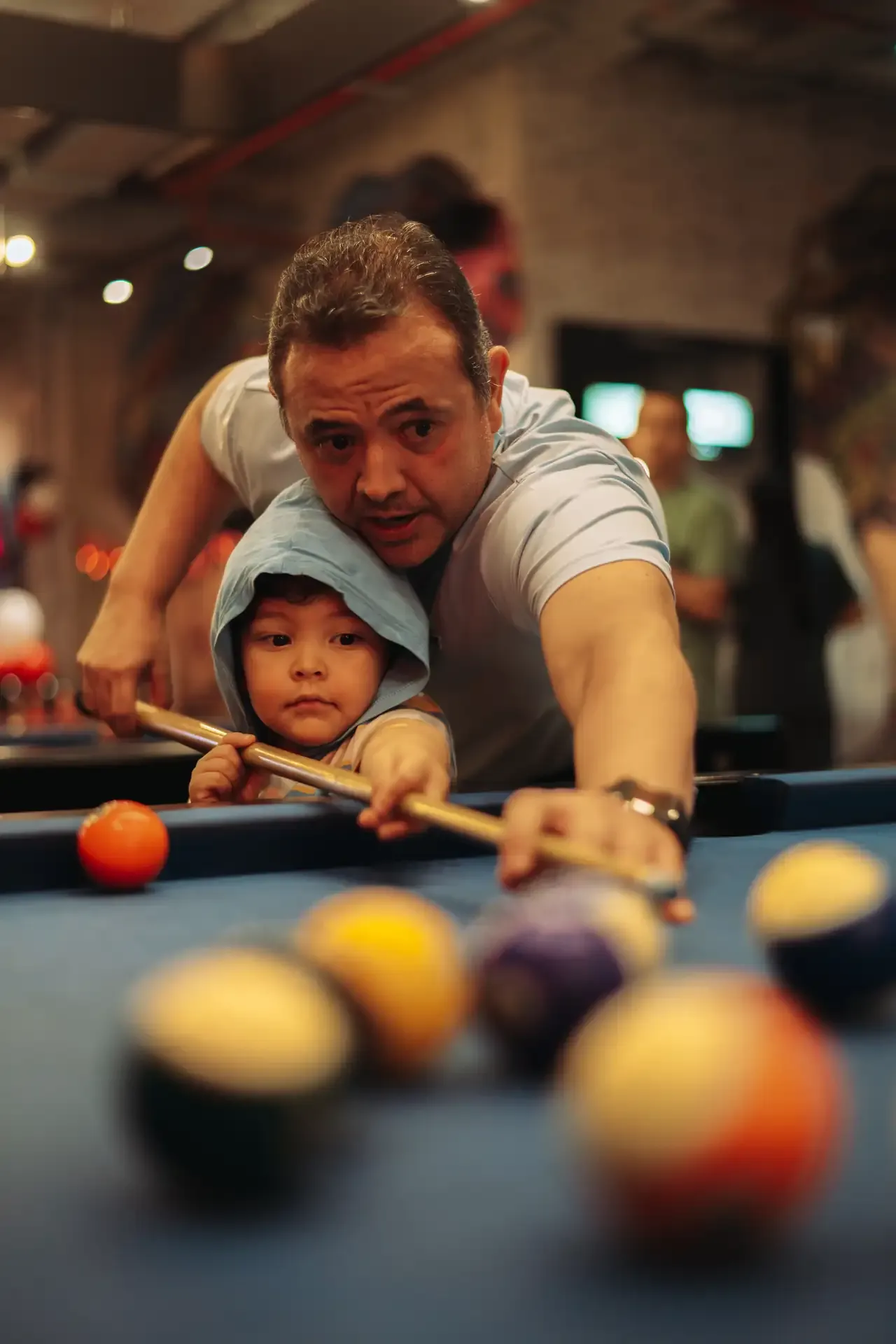 Padre e hijo juegan juntos en la mesa de billar.