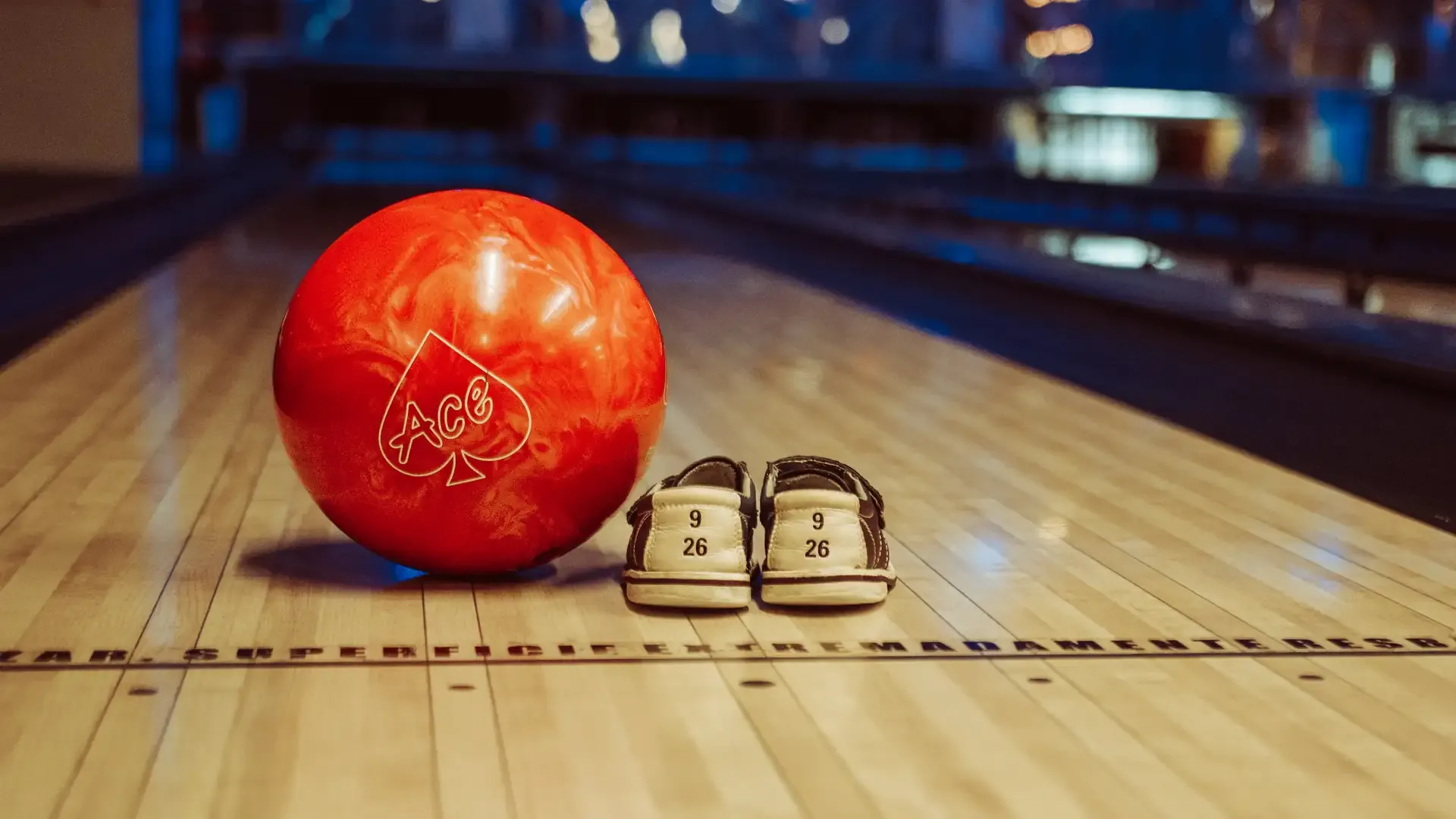 Bola roja y zapatos de bolos al inicio de la pista.