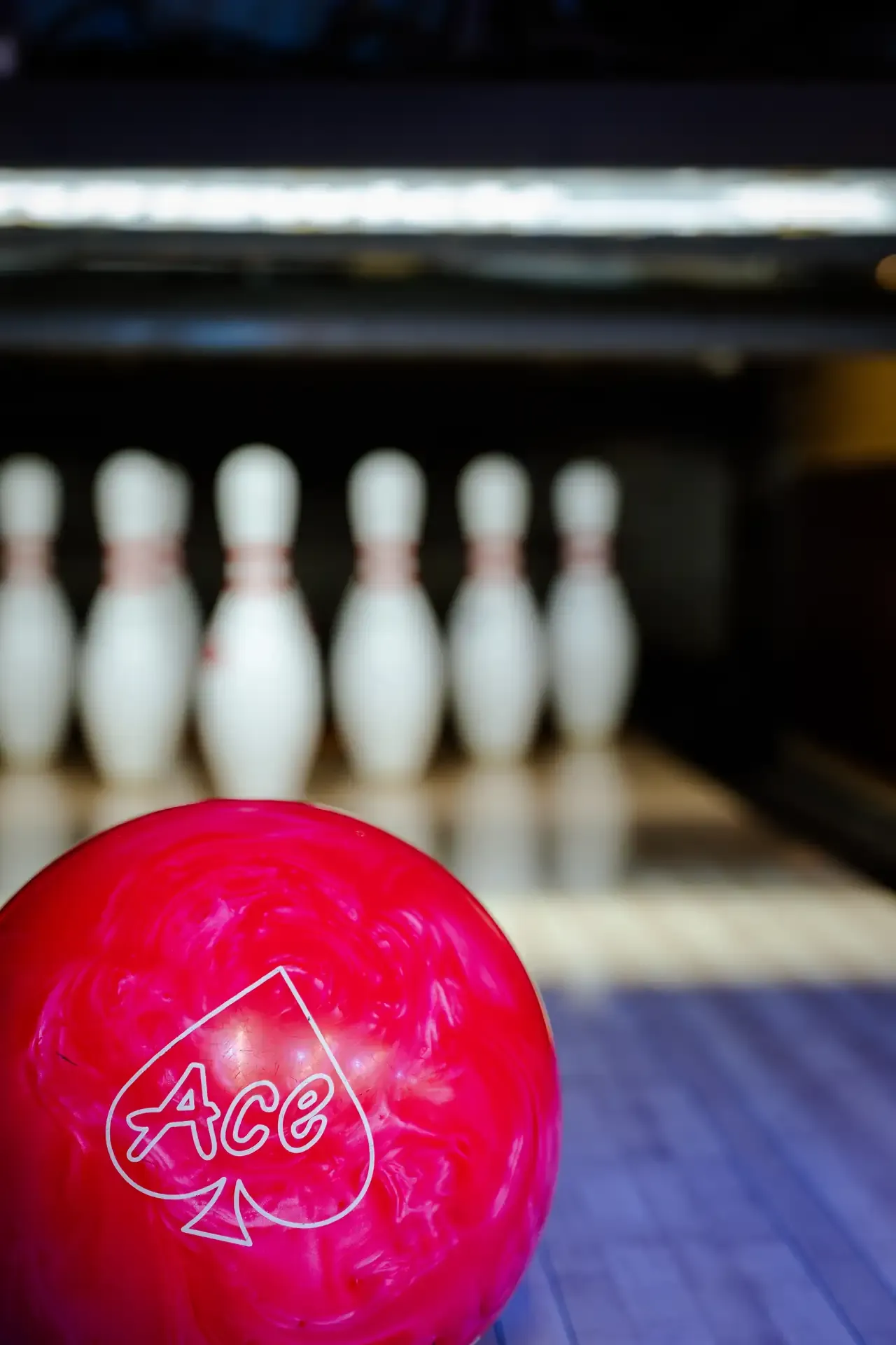 Bola rosada frente a los pinos de bolos.