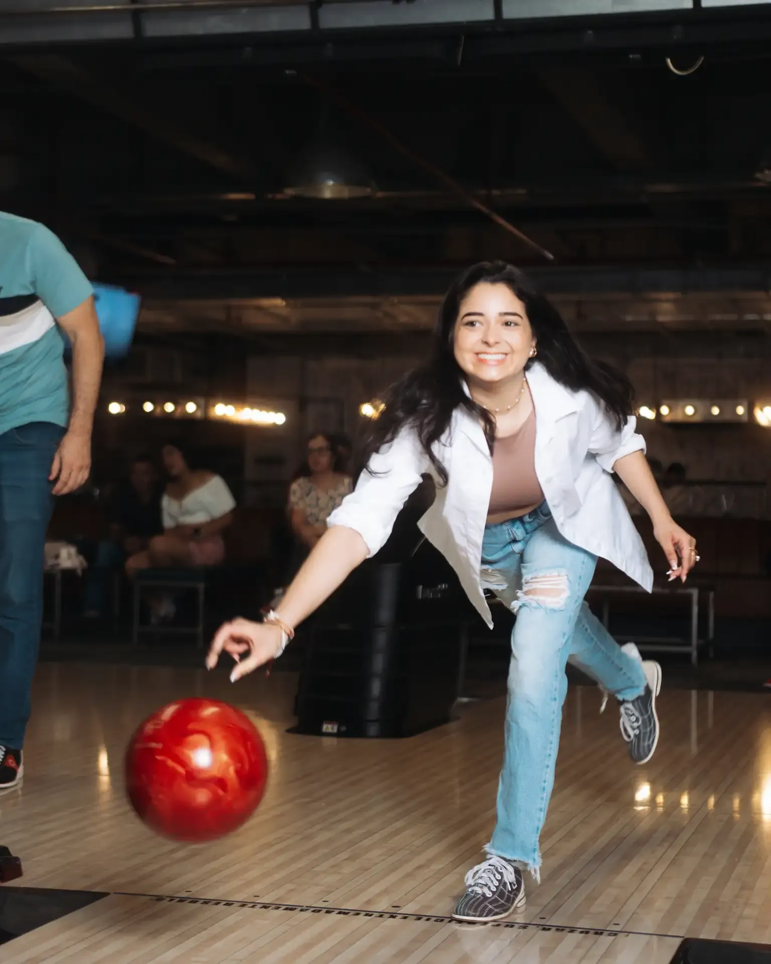 Jugadora lanza una bola roja en la pista.