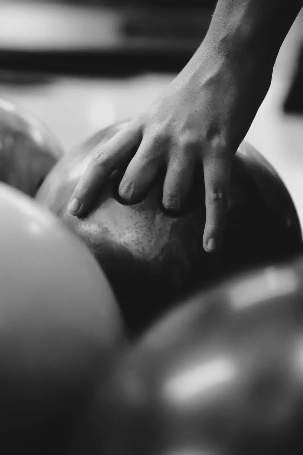 Mano toca una bola de bolos en blanco y negro.
