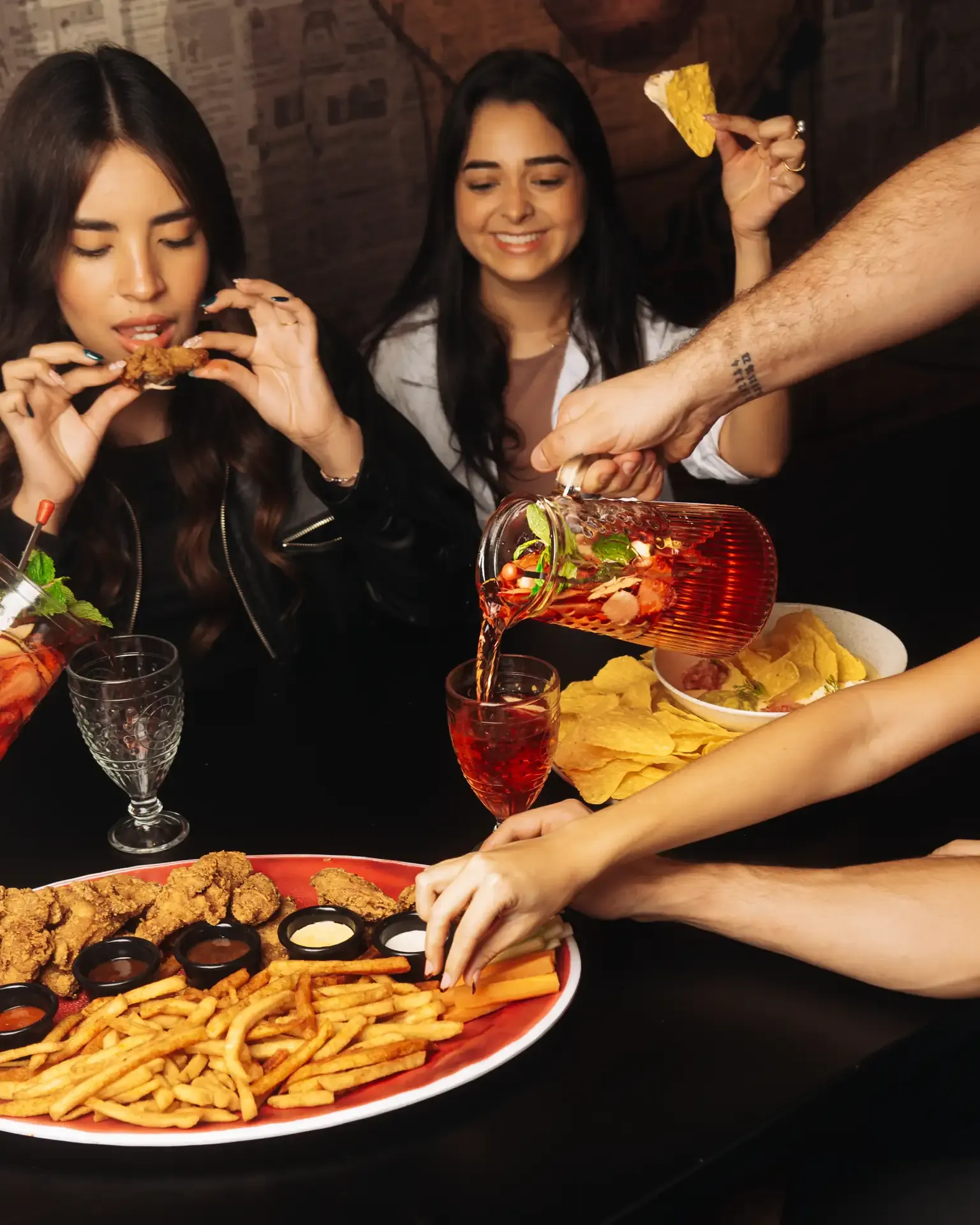 Amigas comparten una comida alrededor de la mesa.