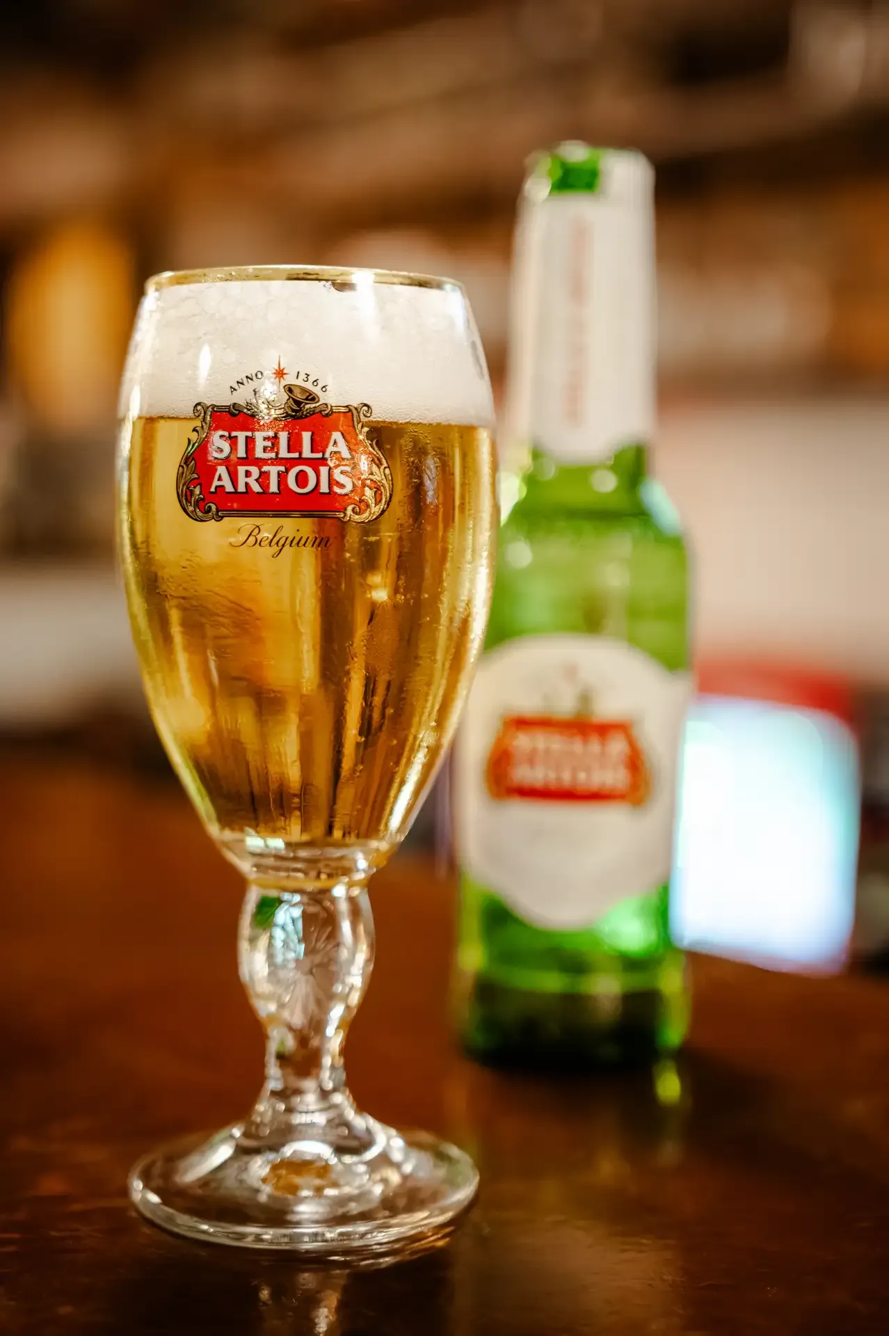 Cerveza servida en copa junto a una botella fría.
