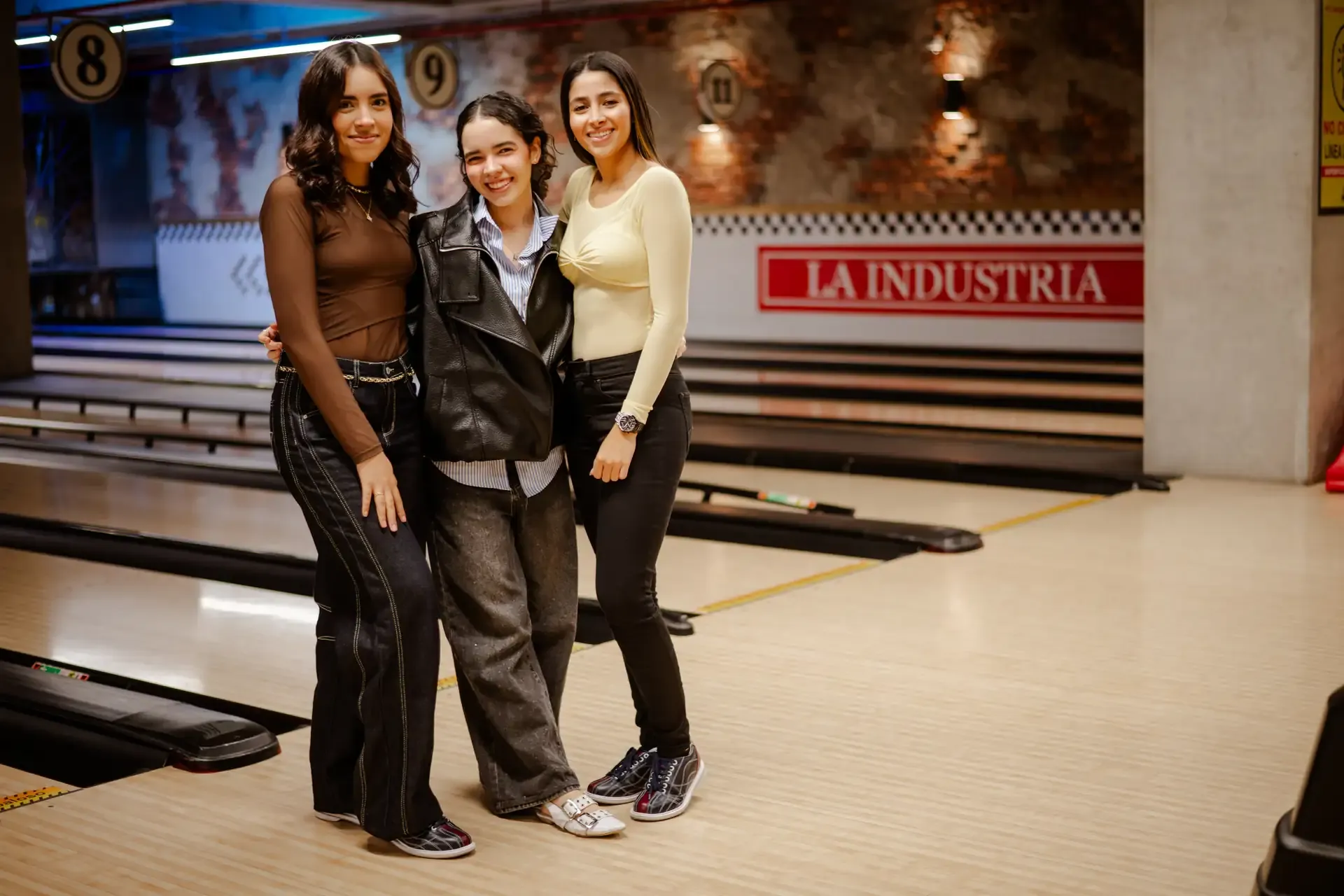 Amigas posan juntas junto a una pista de bolos.