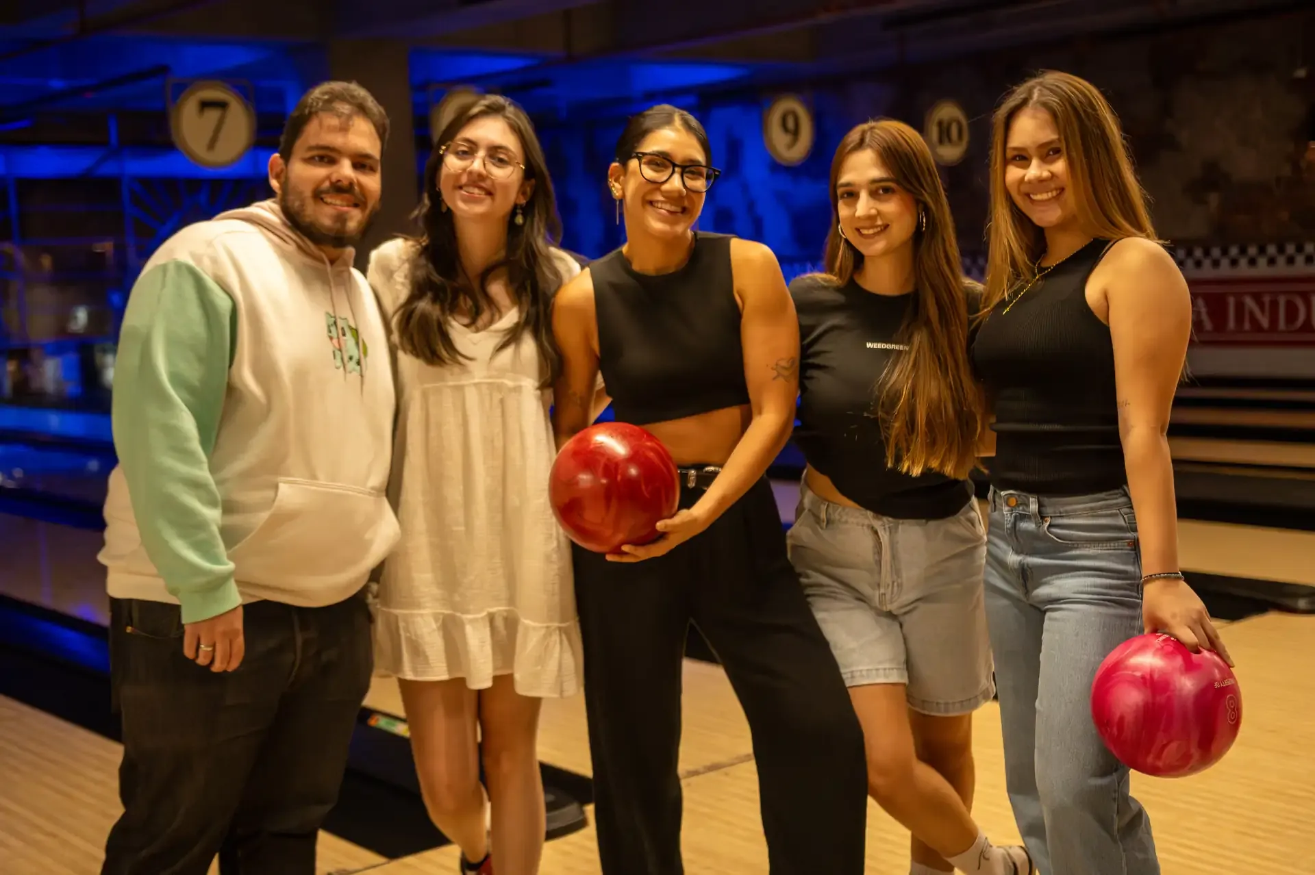 Grupo de amigos posa con bolas de bolos de colores.