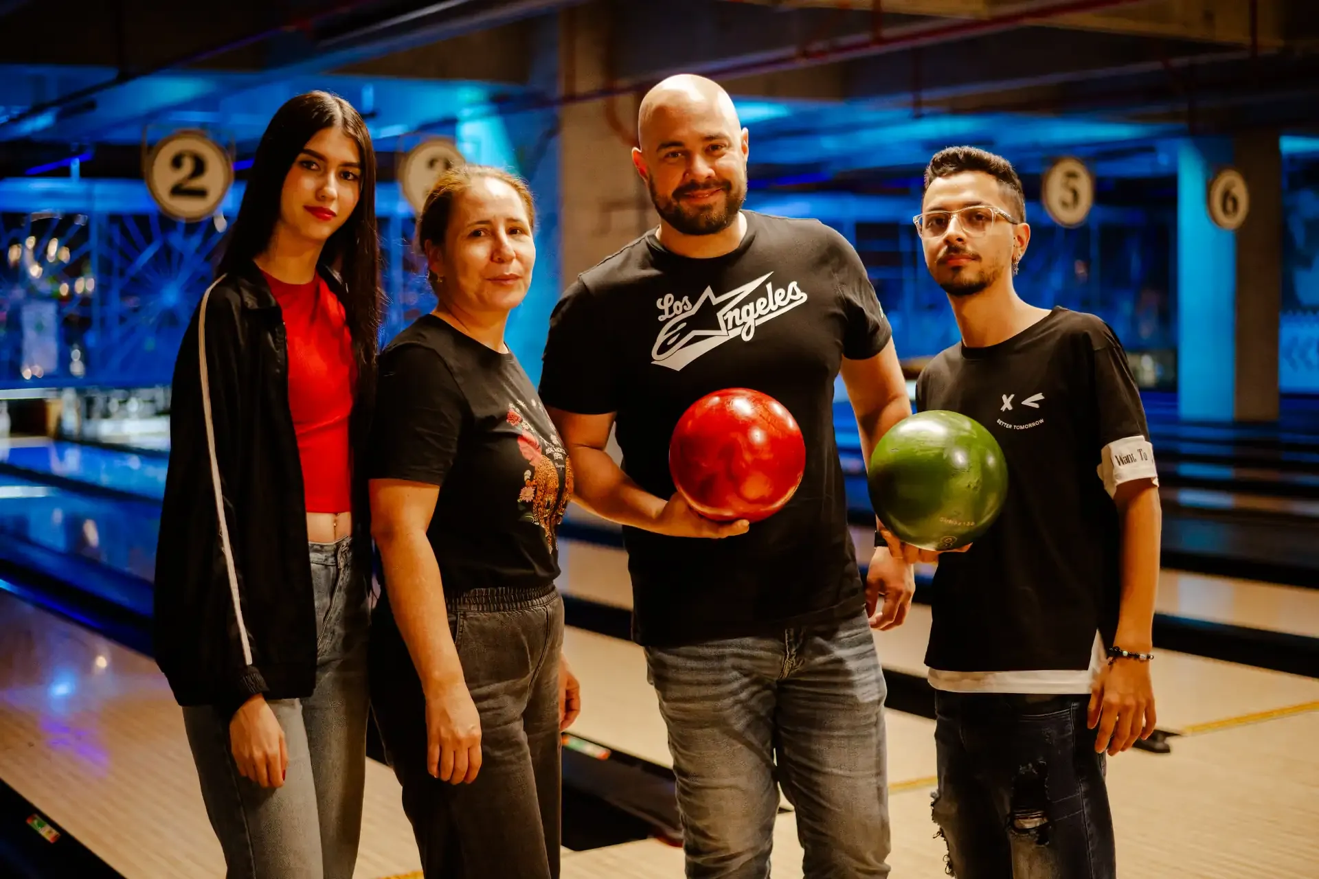 Grupo de amigos posa con bolas de colores en la bolera.