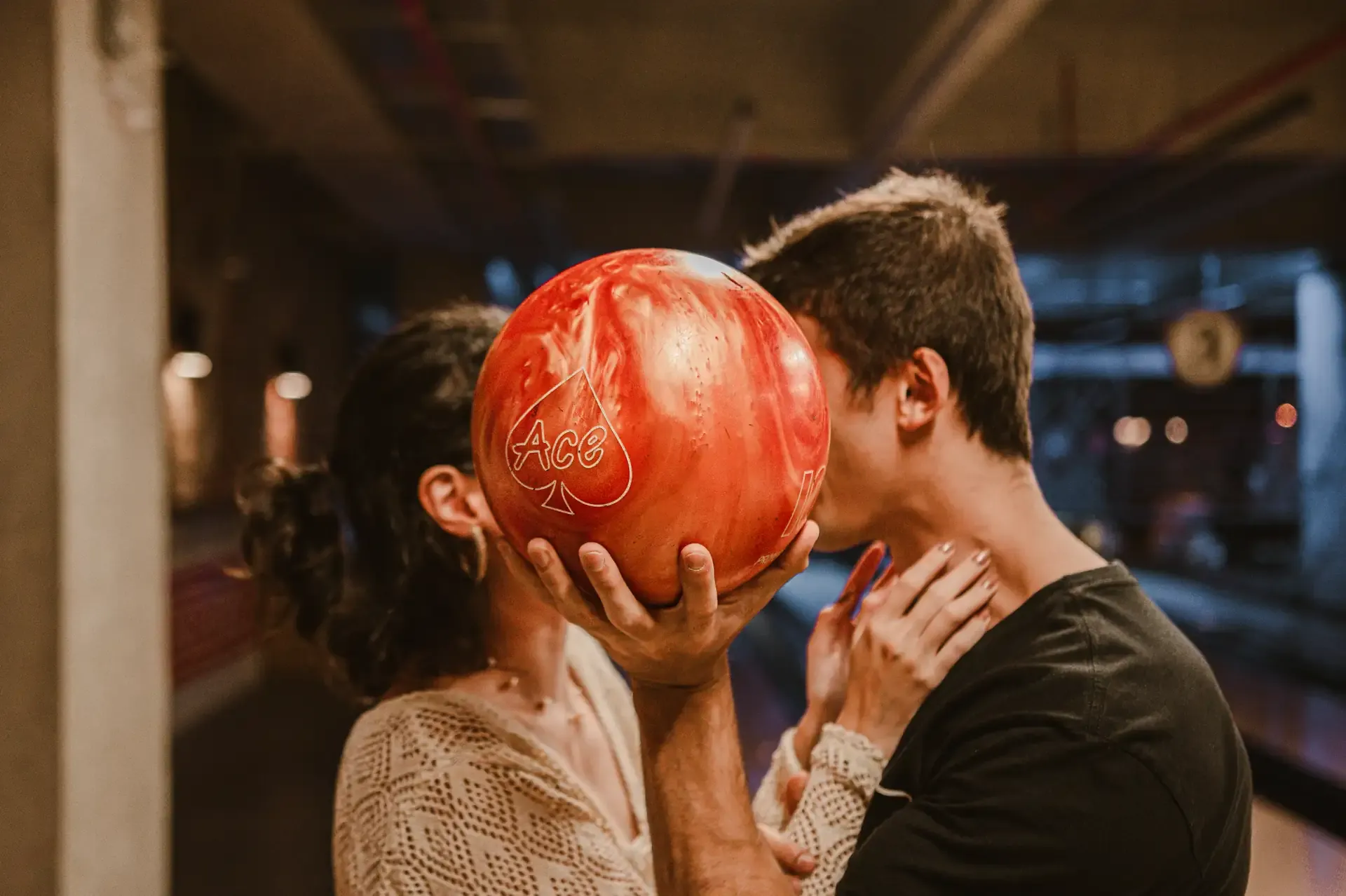 Pareja comparte un momento en la bolera con una bola roja.