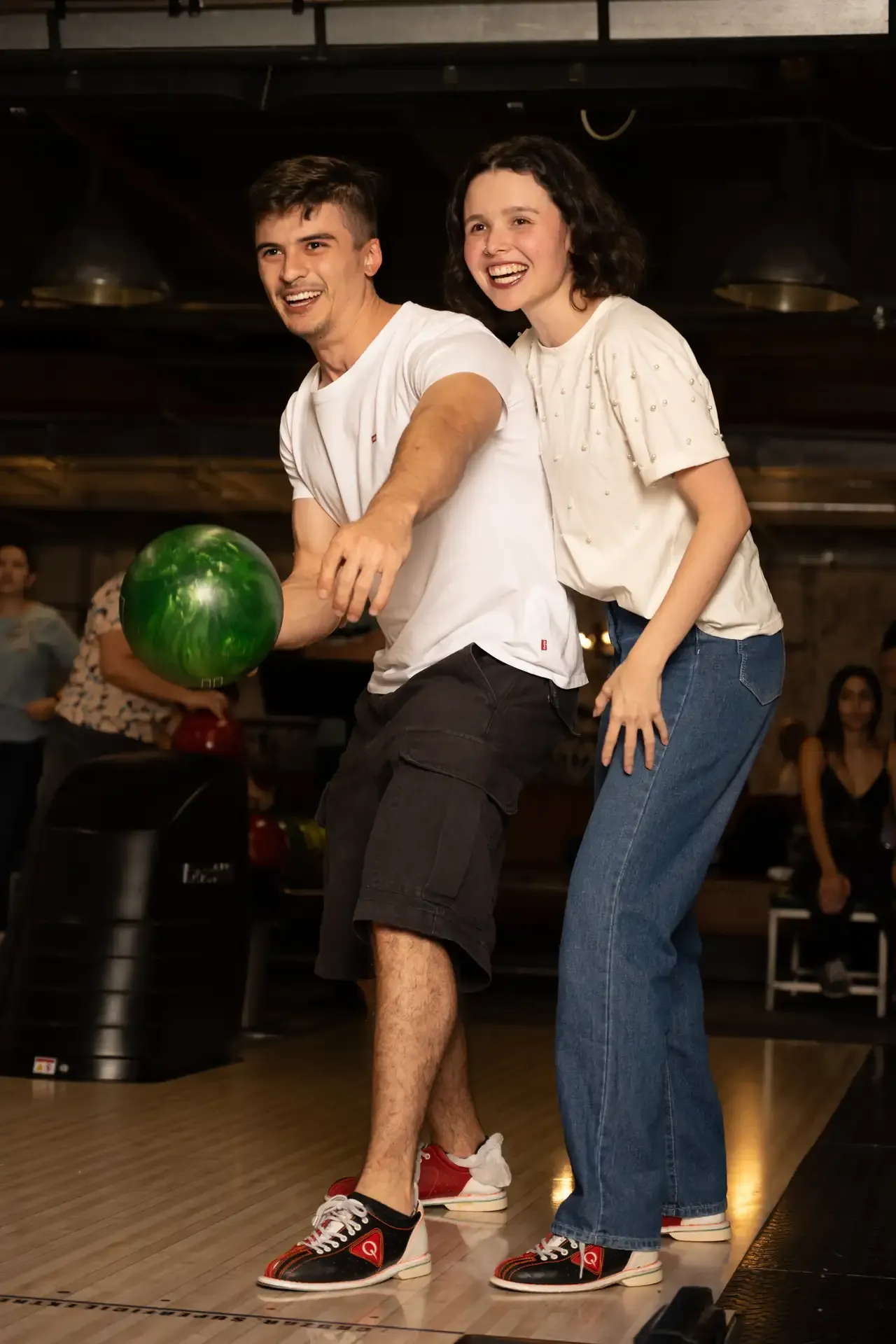Pareja juega con una bola verde en la zona de bolos.