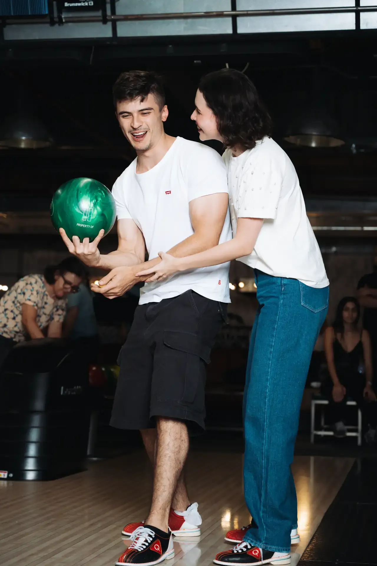 Pareja posa con una bola frente a las pistas.